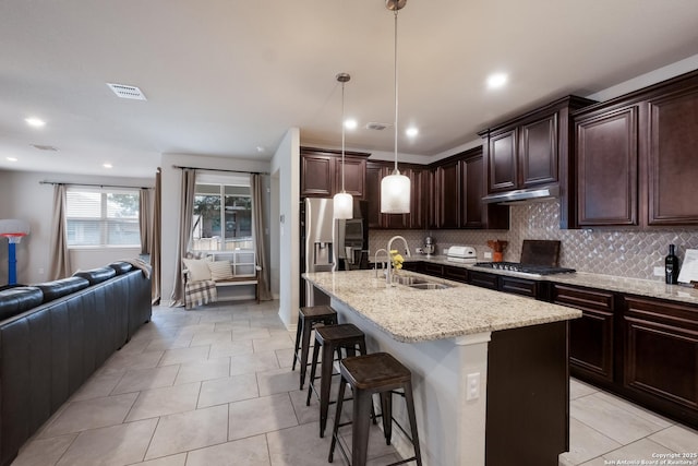 kitchen with under cabinet range hood, stainless steel appliances, a sink, visible vents, and open floor plan