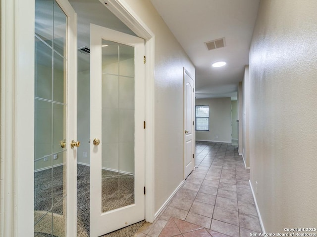 corridor with light tile patterned flooring, visible vents, and baseboards