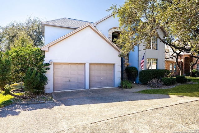 view of front of house featuring a garage, concrete driveway, and stucco siding