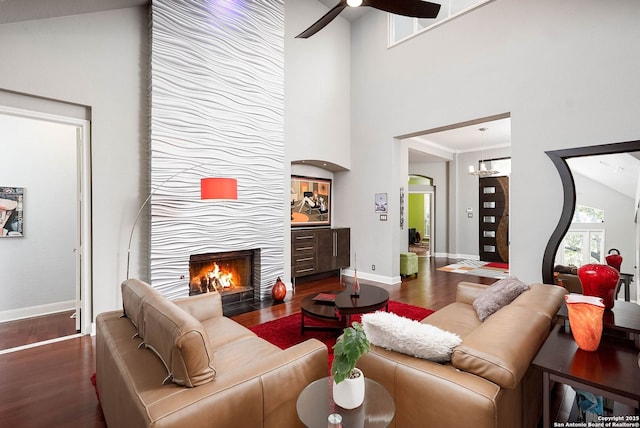 living area with ceiling fan, a fireplace, wood finished floors, and baseboards