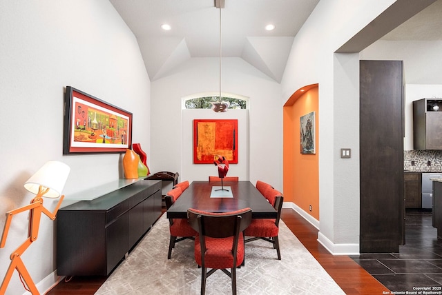 dining space featuring dark wood-style floors, arched walkways, recessed lighting, vaulted ceiling, and baseboards