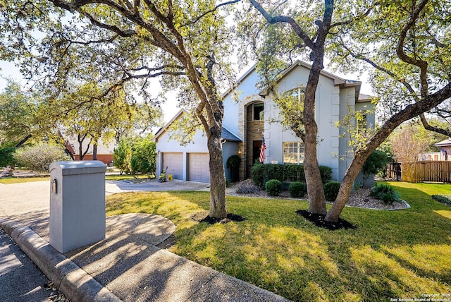 view of front facade with driveway, an attached garage, fence, a front lawn, and stucco siding