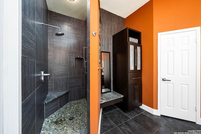 full bathroom featuring tile patterned flooring, tiled shower, and a textured ceiling