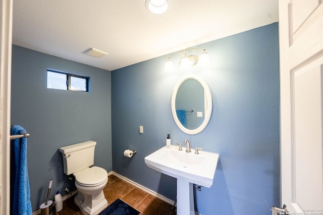 half bathroom featuring toilet, baseboards, and visible vents