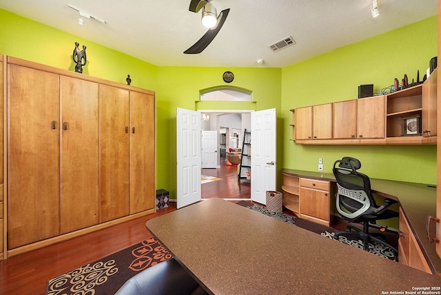 office space featuring dark wood-style floors, lofted ceiling, visible vents, built in study area, and ceiling fan