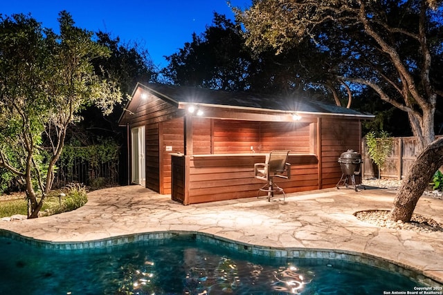 view of outdoor structure featuring fence, a fenced in pool, and an outdoor structure