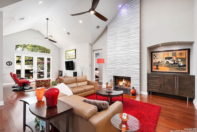 living area with high vaulted ceiling, french doors, a large fireplace, and wood finished floors