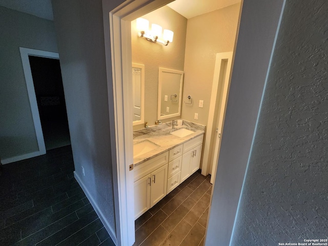 bathroom featuring wood finish floors, a sink, baseboards, and double vanity