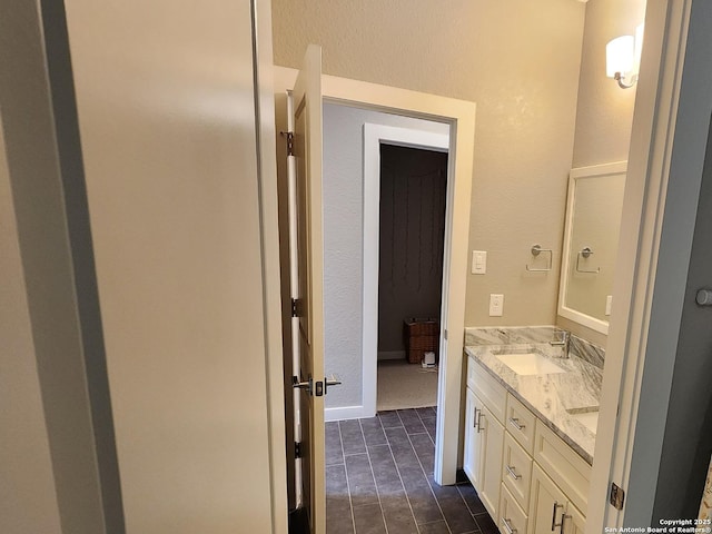 bathroom featuring double vanity, baseboards, and a sink