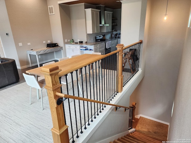 staircase with wood finished floors, visible vents, and baseboards