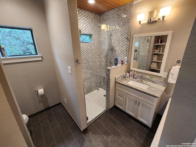 bathroom with a textured wall, wood tiled floor, a walk in shower, and vanity