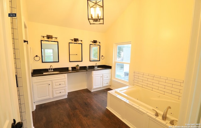 bathroom with lofted ceiling, double vanity, a tub with jets, and a sink