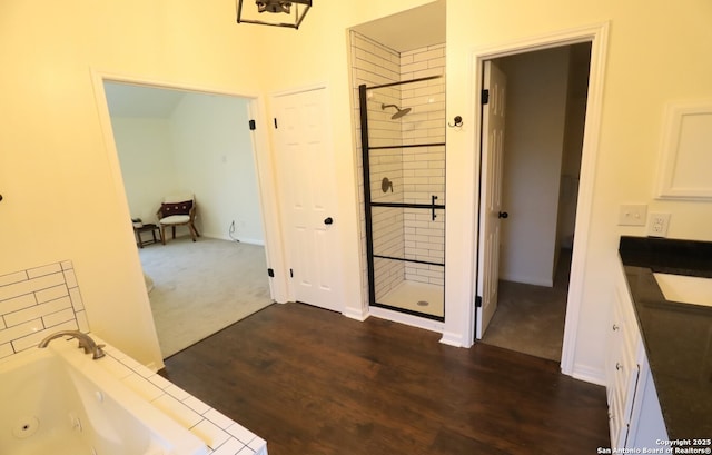 bathroom with a stall shower, vanity, a tub with jets, and wood finished floors