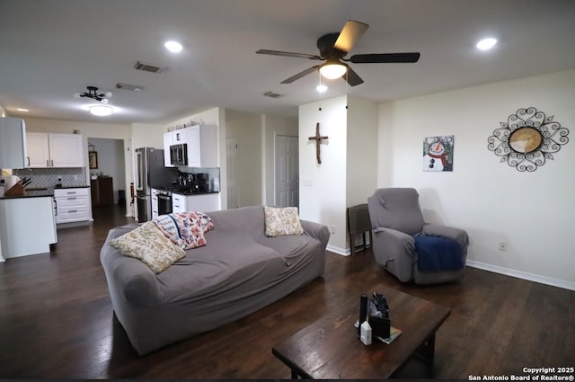 living area with visible vents, dark wood finished floors, baseboards, and ceiling fan