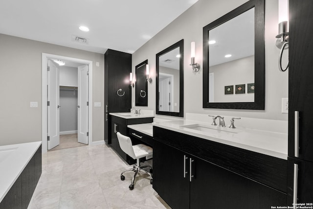 bathroom featuring a walk in closet, recessed lighting, visible vents, vanity, and baseboards