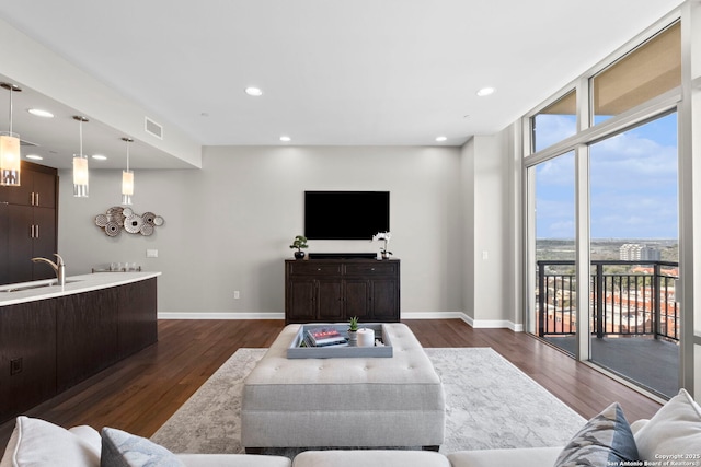 living room featuring baseboards, floor to ceiling windows, visible vents, and dark wood-type flooring