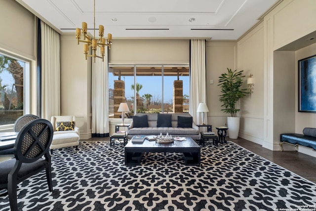 living room with a chandelier, a decorative wall, and wood finished floors