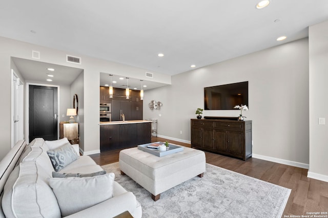 living area featuring recessed lighting, dark wood-style flooring, visible vents, and baseboards