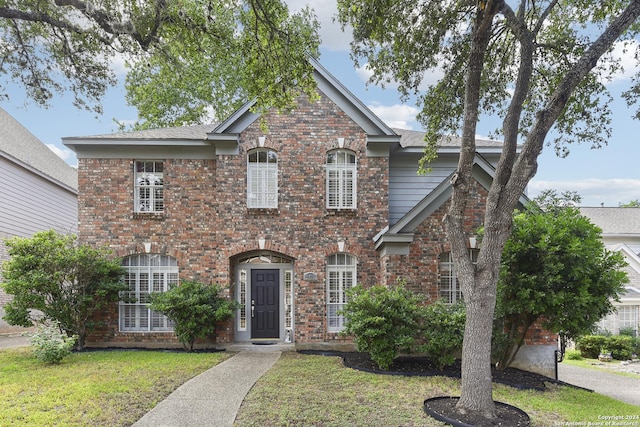 traditional-style home with brick siding and a front yard