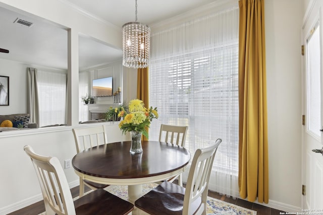 dining area with baseboards, visible vents, wood finished floors, an inviting chandelier, and crown molding