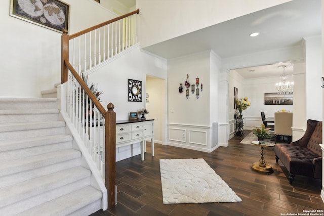 interior space featuring wood finish floors, crown molding, a decorative wall, an inviting chandelier, and stairs