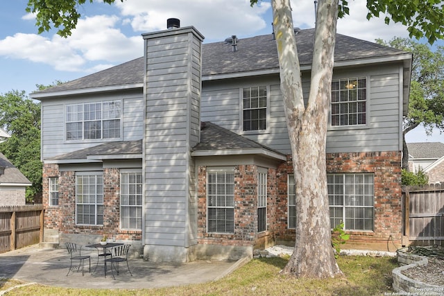 rear view of property with brick siding, fence, a chimney, and a patio