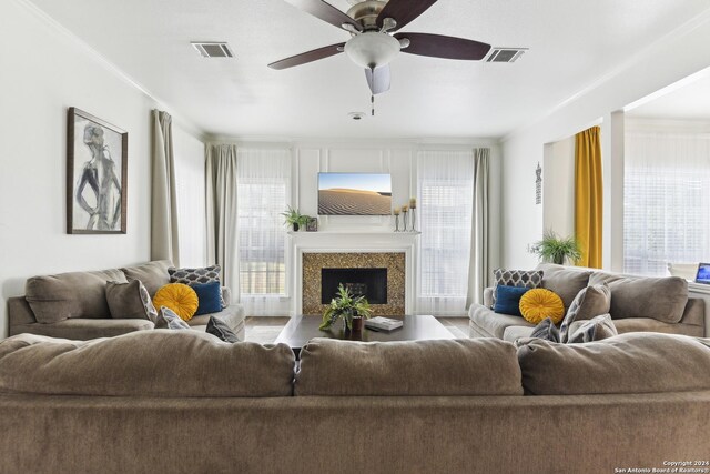 living room featuring ornamental molding, visible vents, ceiling fan, and a premium fireplace