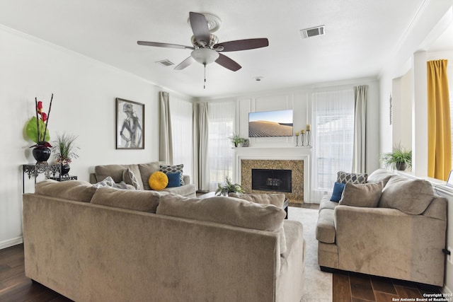 living area featuring crown molding, a premium fireplace, visible vents, and dark wood-type flooring