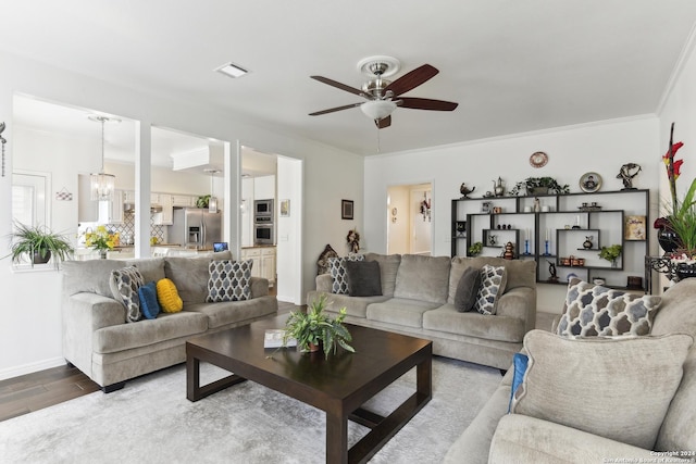 living room with ceiling fan with notable chandelier, ornamental molding, wood finished floors, and visible vents