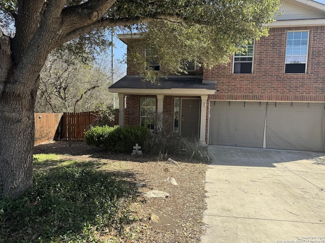 traditional-style home featuring a garage, concrete driveway, brick siding, and fence