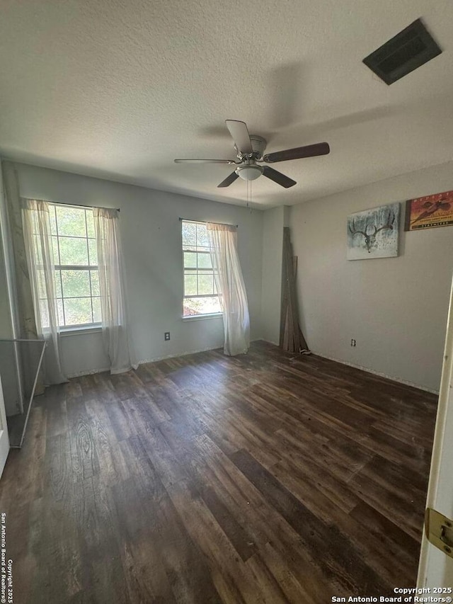 empty room with a healthy amount of sunlight, a textured ceiling, and wood finished floors