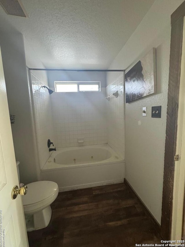 bathroom featuring visible vents, toilet, a textured ceiling, wood finished floors, and  shower combination