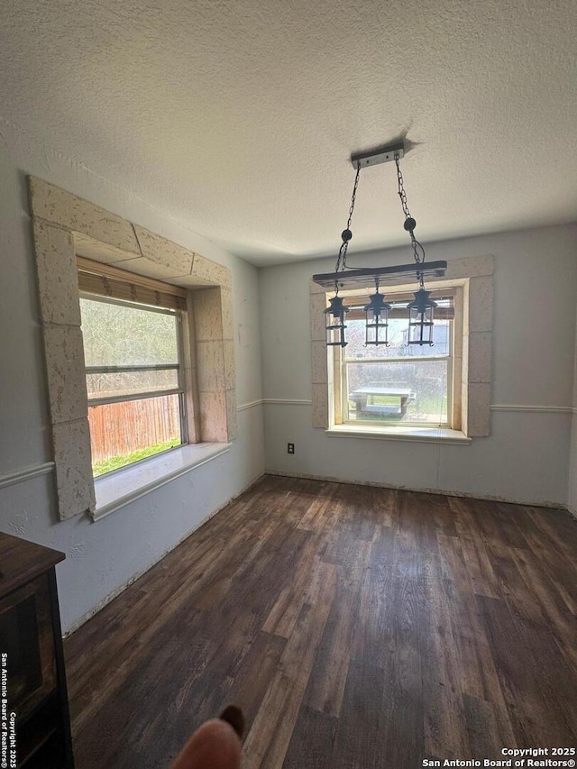 unfurnished dining area with a textured ceiling and wood finished floors