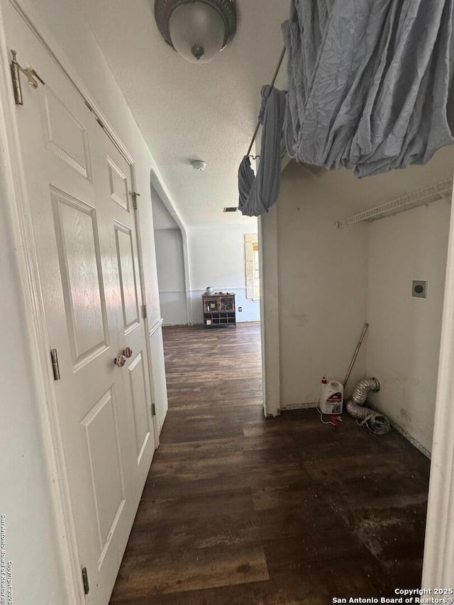 corridor with a textured ceiling and wood finished floors