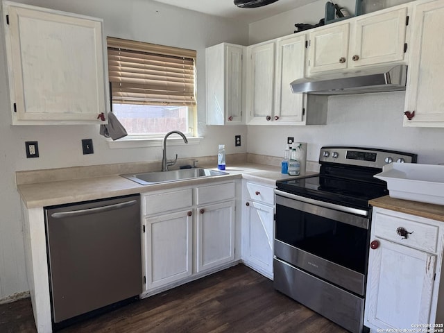 kitchen featuring dark wood-style flooring, light countertops, appliances with stainless steel finishes, a sink, and under cabinet range hood