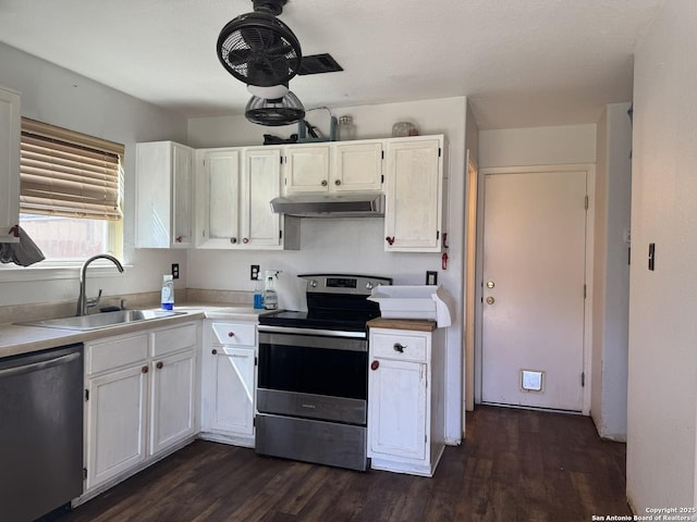 kitchen featuring dark wood-style floors, stainless steel appliances, under cabinet range hood, white cabinetry, and a sink