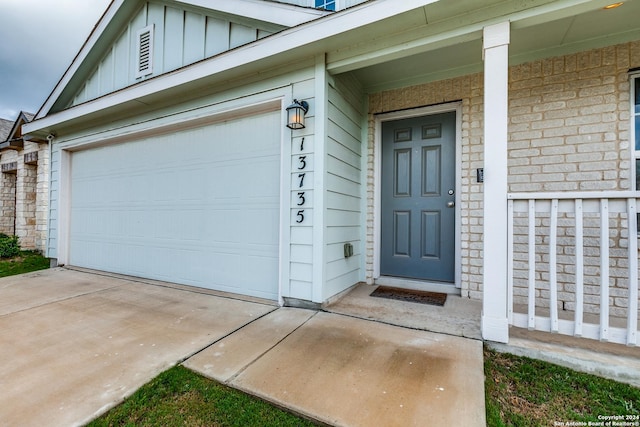 property entrance featuring board and batten siding, driveway, and a garage