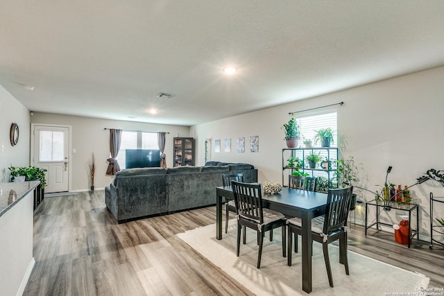 dining area featuring a wealth of natural light, light wood-type flooring, visible vents, and baseboards