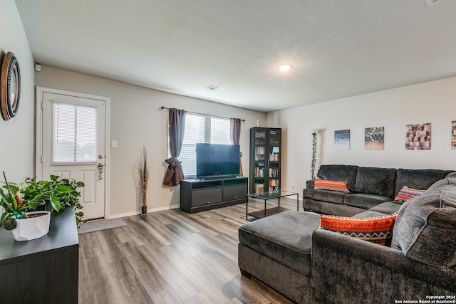 living room with visible vents, a textured ceiling, baseboards, and wood finished floors