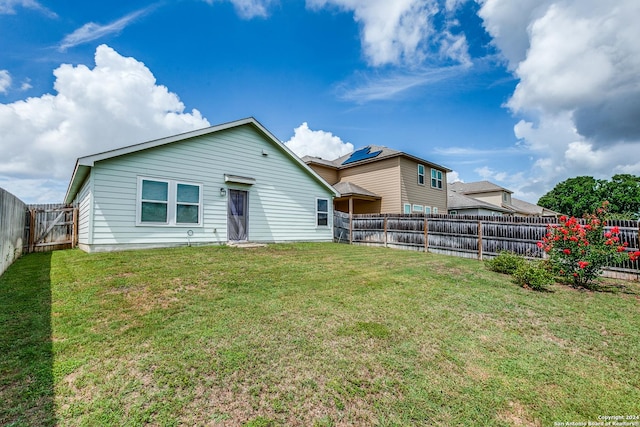 rear view of house with a fenced backyard and a yard