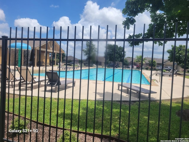 community pool with fence, a lawn, and a patio
