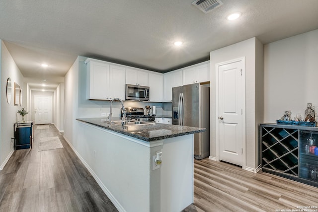 kitchen featuring stainless steel appliances, white cabinets, visible vents, and light wood finished floors
