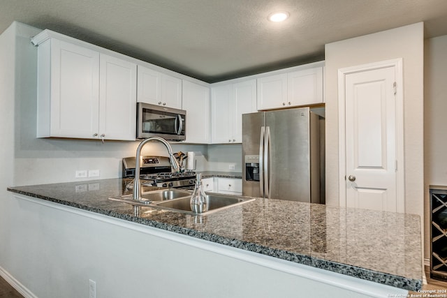 kitchen with stainless steel appliances, white cabinets, a peninsula, and a textured ceiling