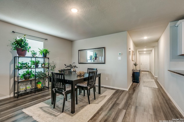 dining area with dark wood-style floors, baseboards, and a textured ceiling