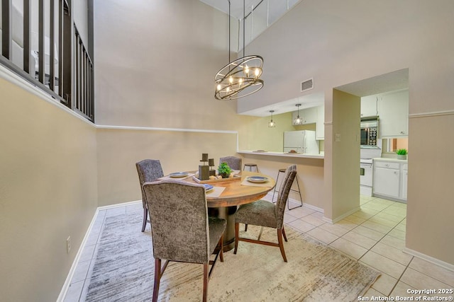 dining space featuring a high ceiling, visible vents, baseboards, and light tile patterned flooring