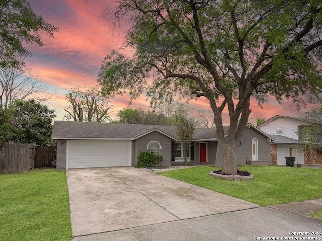 view of front of property featuring a garage, driveway, fence, and a yard