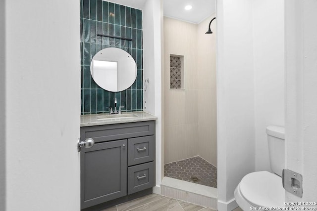 full bath featuring toilet, a tile shower, tile walls, and vanity