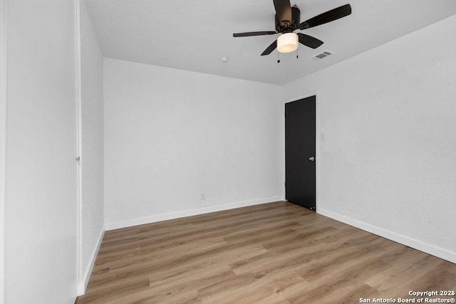 spare room featuring light wood-type flooring, baseboards, visible vents, and ceiling fan