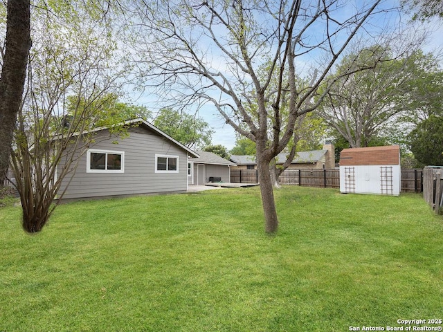 view of yard with a storage shed, a fenced backyard, and an outbuilding