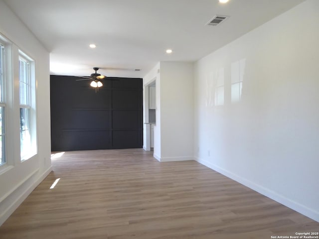 empty room featuring recessed lighting, visible vents, a ceiling fan, light wood-type flooring, and baseboards